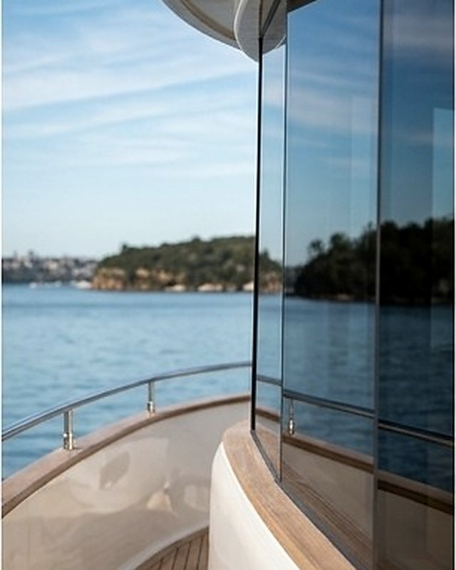 Teak side deck and curved glass running aft along a motor cruiser