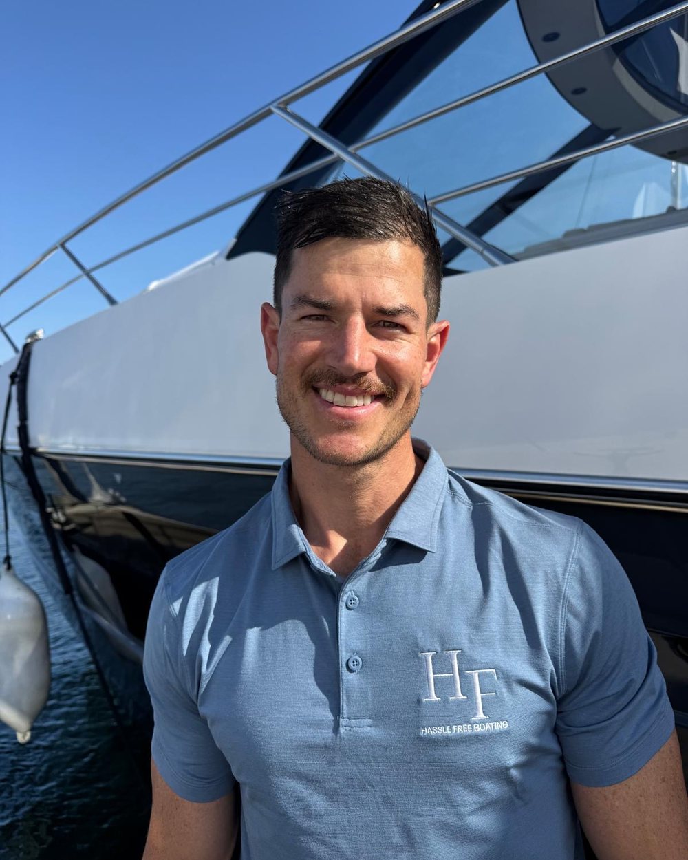 Esti De Swardt, founder of Hassle Free Boating, beside a motor yacht in the company polo