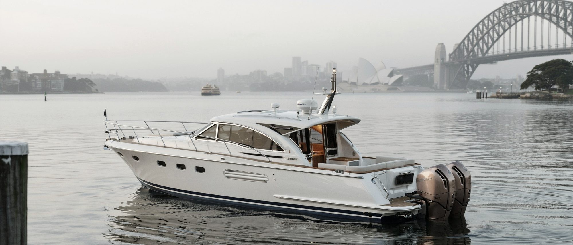Motor yacht on still water at first light, Sydney Harbour Bridge and Opera House soft in the haze behind