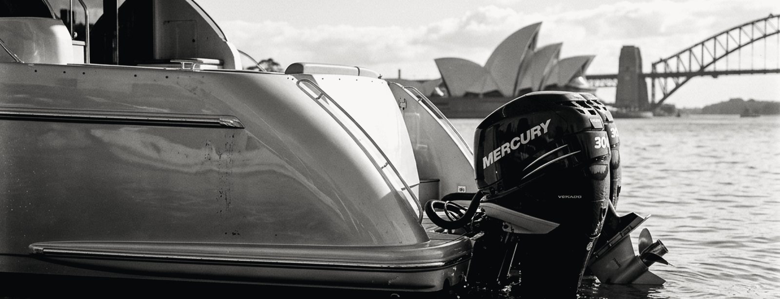 Outboard engines on the stern of a cruiser with the Sydney Opera House in the distance