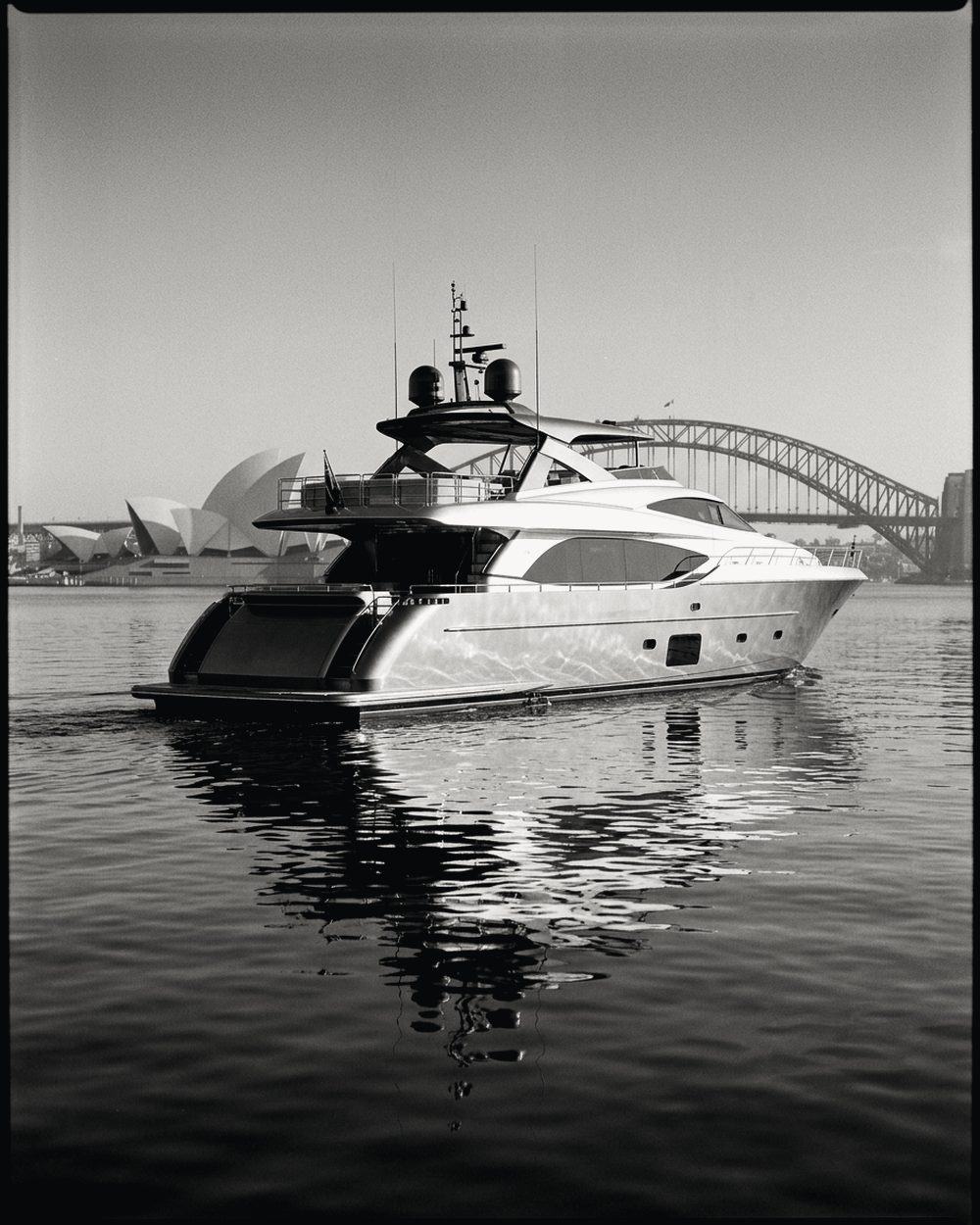 Motor yacht on still water off Sydney, the Opera House and Harbour Bridge behind