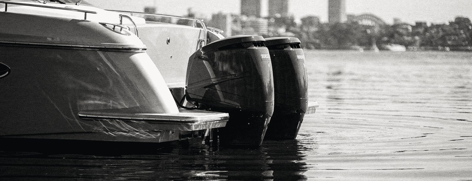 Motor cruisers at rest on flat water with the Sydney skyline behind