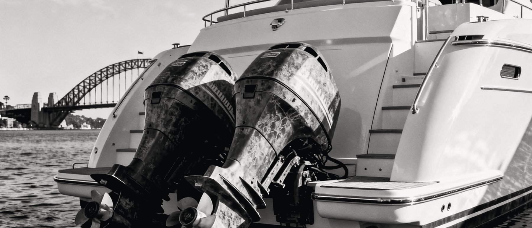 Twin outboards on the stern of a motor cruiser, the Sydney Harbour Bridge behind