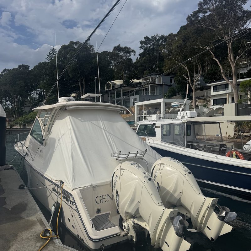 Cruiser under its cockpit cover, twin outboards tilted up at the berth