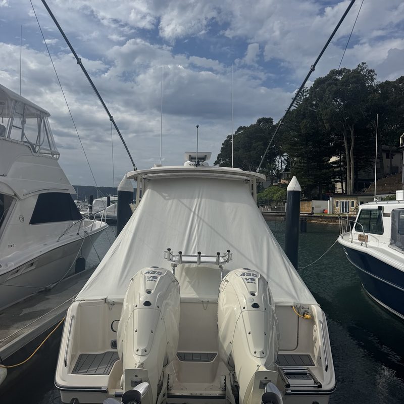 Stern of a covered cruiser with twin outboards, moored at a marina