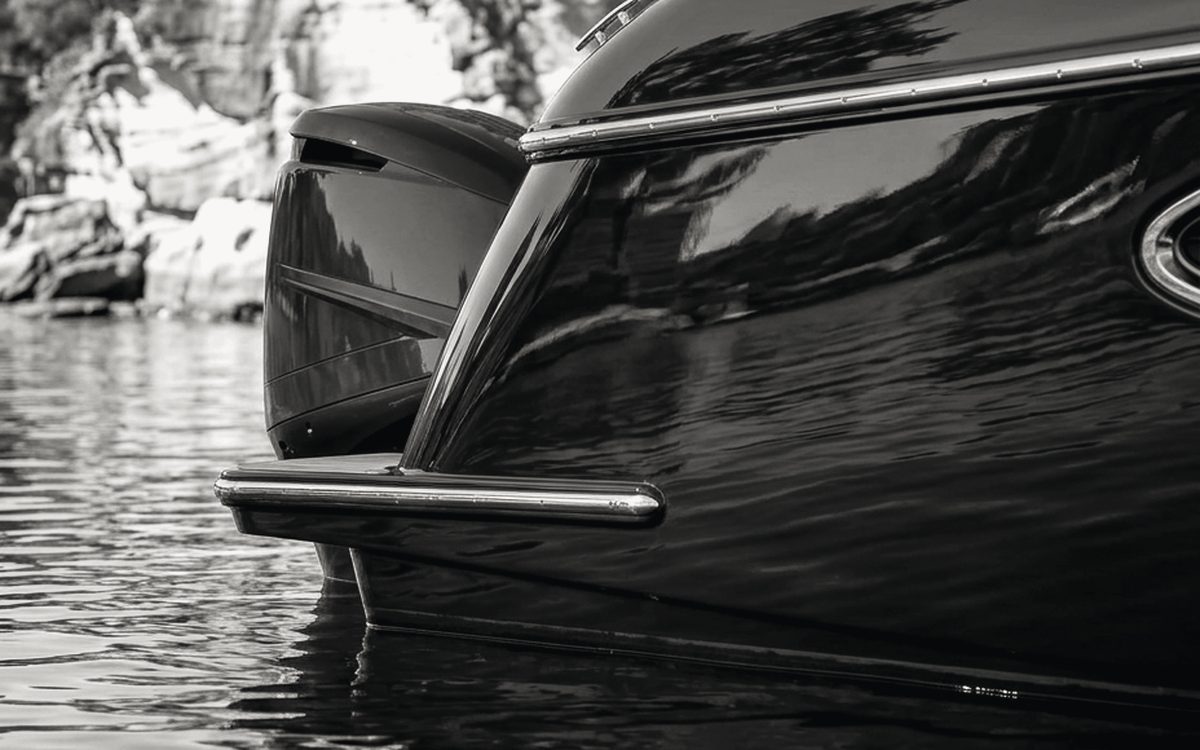Close view of a polished dark hull reflecting the shoreline, showing a mirror-finish detail