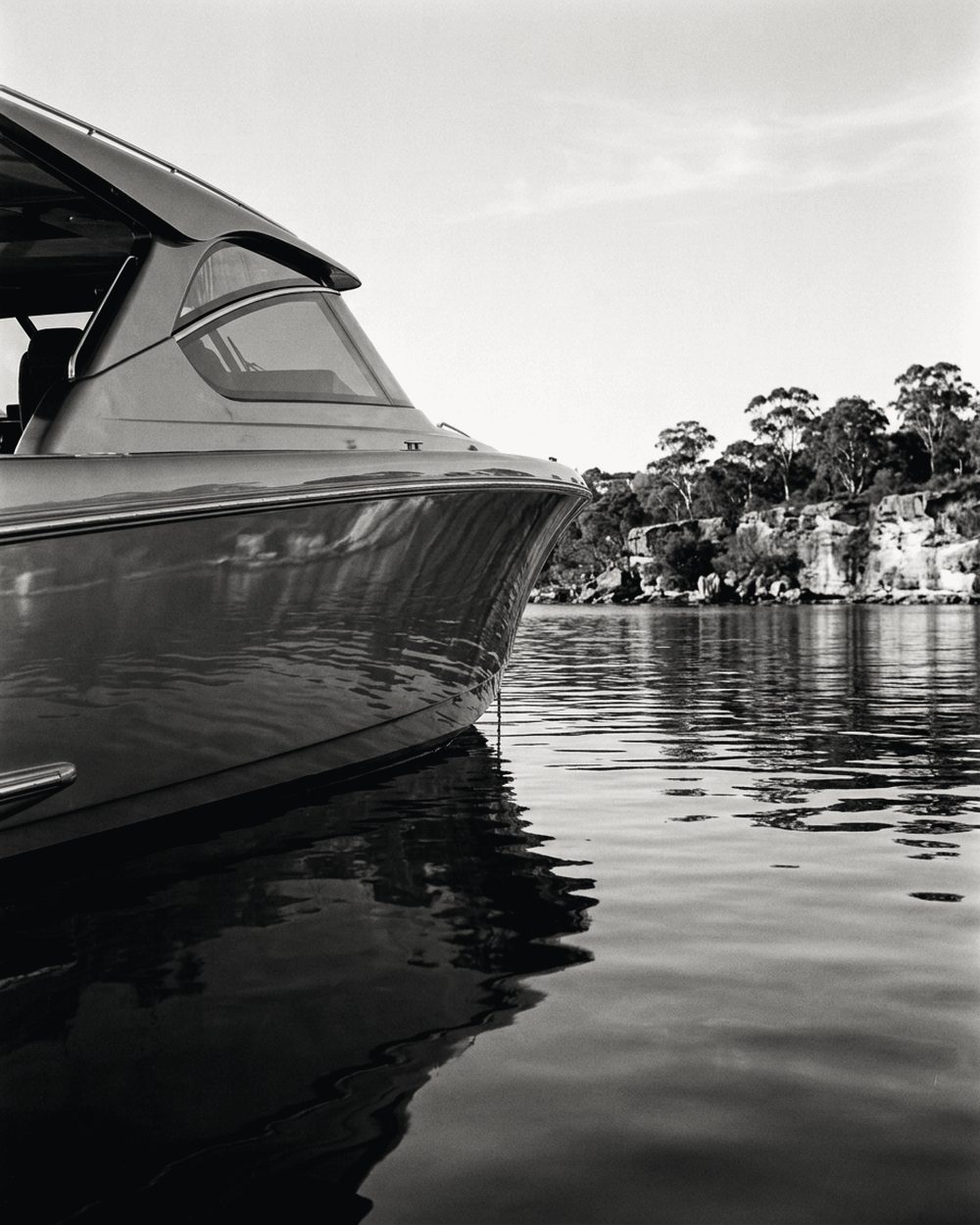 Polished bow and hull of a motor cruiser on still water